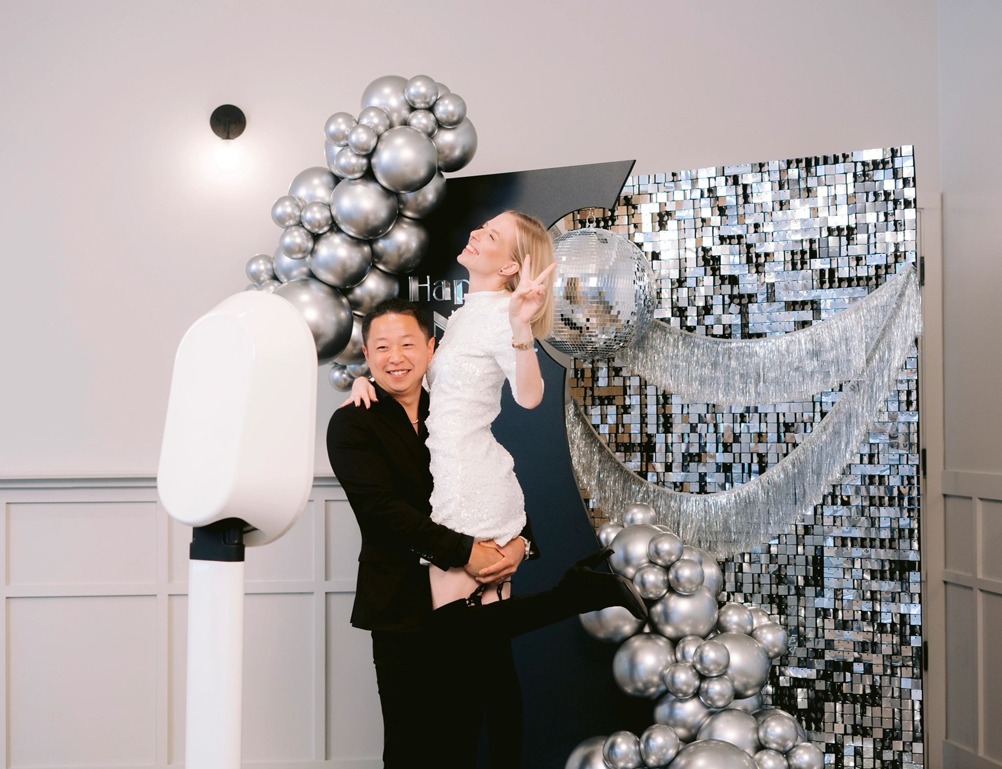 Couple celebrating with silver balloons and decorations.